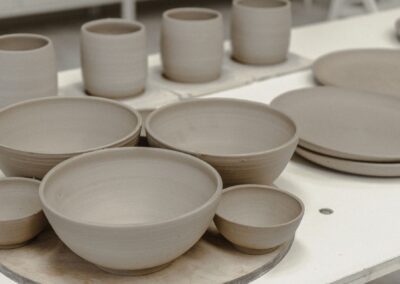 A collection of handmade pottery bowls and mugs in a workshop setting, showcasing craftsmanship.